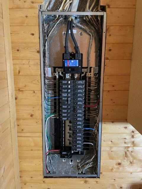 Open electrical panel showing breakers and branch-circuit wiring
